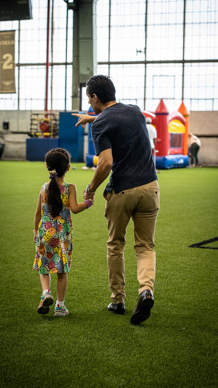 Sinan Erdemir walking hand in hand with a young girl at an indoor family sports event