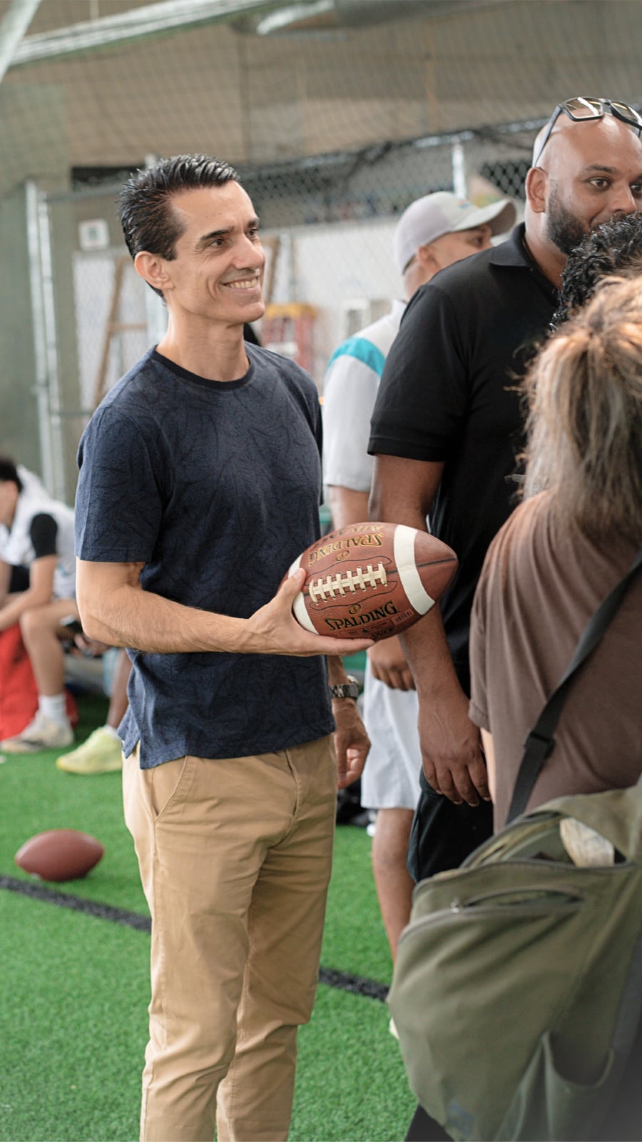 Sinan Erdemir holding a football at an indoor community sports event
