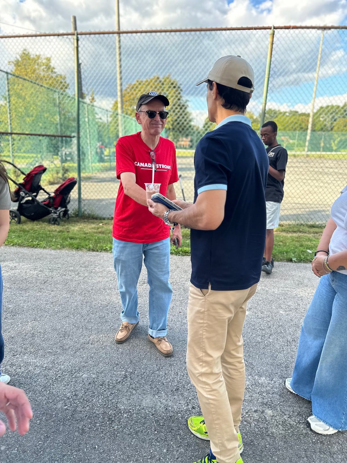 Sinan Erdemir talking with a resident beside the ball diamond at a park event