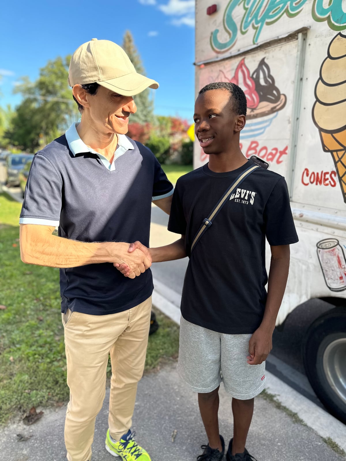 Sinan Erdemir shaking hands with a young resident beside an ice cream truck